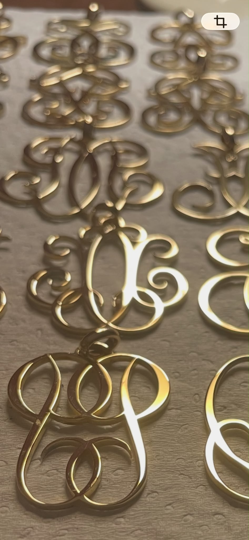 Collection de monogrammes en or disposés sur un plan de travail, vue de l'atelier